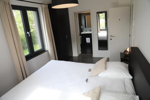 a bedroom with a white bed and a window at Hôtel Restaurant Lamy in Troisvierges