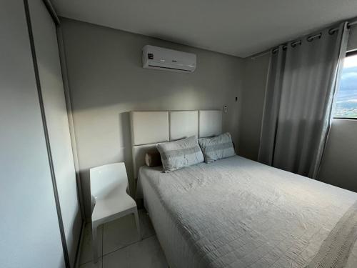 a small bedroom with a bed and a white chair at Suite Master Casa Luz in Garanhuns