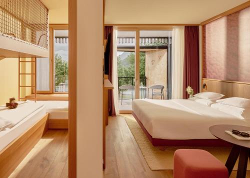 a hotel room with two beds and a balcony at Falkensteiner Family Hotel Montafon - The Leading Hotels of the World in Tschagguns