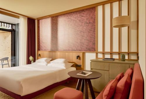 a hotel room with a bed and a table at Falkensteiner Family Hotel Montafon - The Leading Hotels of the World in Tschagguns