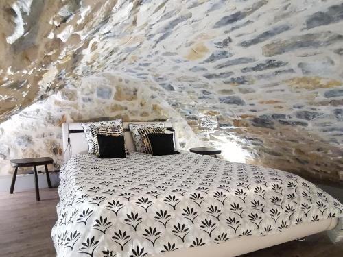 a bed in a room with a stone wall at Gorge du Tarn Loft Cocoon Lesoleilo in Mostuéjouls