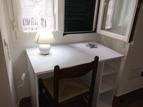 einen weißen Schreibtisch mit einer Lampe und einem Stuhl in der Unterkunft Casetta zia Tetti in Lecce