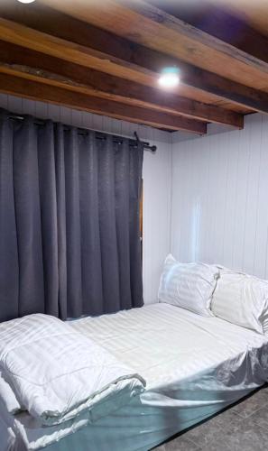 ein Bett in einem Zimmer mit einem grauen Vorhang in der Unterkunft Datu Villa Sembalun in Sembalun Lawang