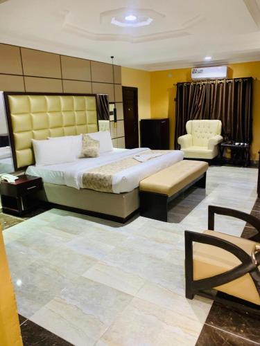a hotel room with a large bed and a chair at Excellence Citizens Hotel and Resort in Ilorin