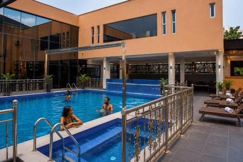 a group of people in a swimming pool next to a building at Excellence Citizens Hotel and Resort in Ilorin