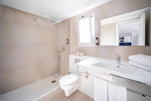 a white bathroom with a toilet and a sink at Serenity Apartments in Port d'Alcudia