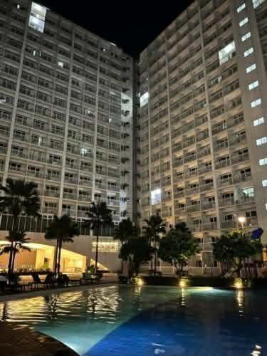 a large building with a large swimming pool at night at Shore 1 Tower D in Manila