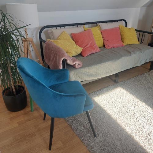 a blue chair in front of a couch with colorful pillows at Panorama Wine & Chill in Hévíz