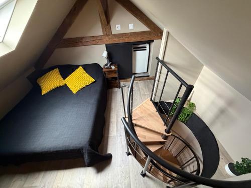 an attic room with a bed and a spiral staircase at L'Escapade Normande in Caen