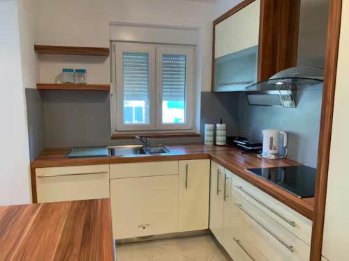 a kitchen with white cabinets and a sink and a window at Apartments Kivi in Novigrad Istria