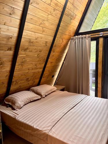 a bed in a wooden room with a window at AFRAME Solotvino in Solotvyno