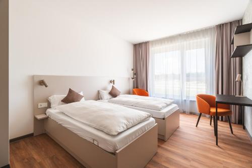 a hotel room with two beds and a desk at Boardinghouse Air Tech Campus - smart Check-in in Weßling