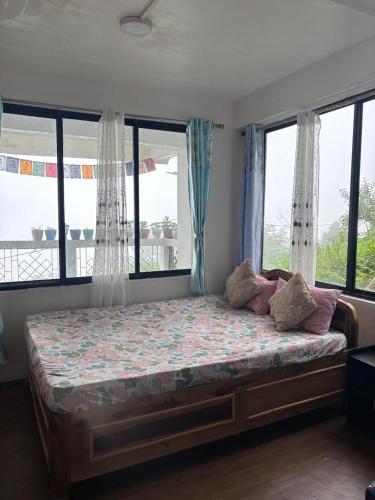 a bed in a room with windows and a bed with pillows at Bravo Hills in Gauhāti