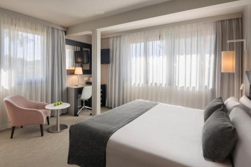 a hotel room with a large bed and a chair at Salles Hotel Aeroport de Girona in Riudellots de la Selva