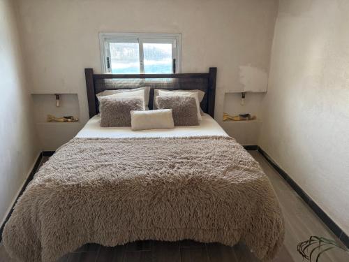 a bedroom with a bed with a blanket and a window at El Tablado Ocean View House in Güimar
