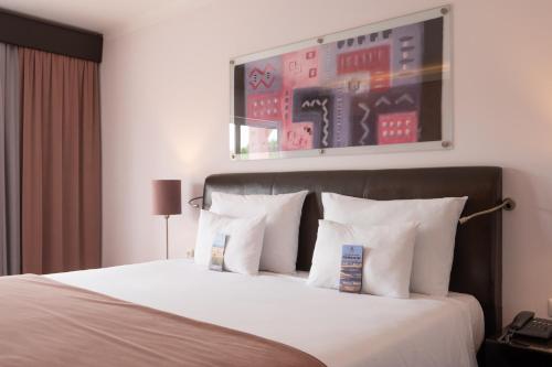 a hotel room with a large bed with white pillows at Vila Gale Collection Praia in Albufeira