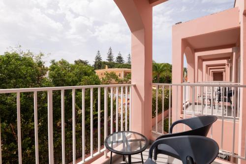 a balcony with chairs and tables on a building at Vila Gale Collection Praia in Albufeira