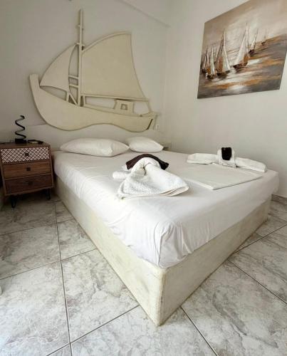ein weißes Bett mit einem Handtuch darauf in einem Schlafzimmer in der Unterkunft Foinikas Studios in Mérikhas