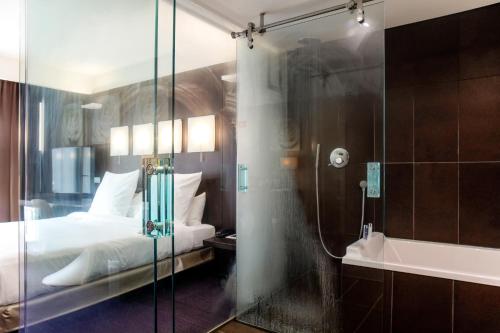 a bedroom with a bed and a shower and a tub at Le Rex Hôtel in Tarbes
