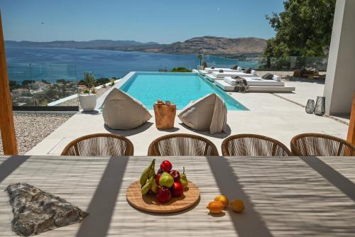 a table with a plate of fruit on it next to a pool at Aethra Villa - Infinity Pool & Panoramic Sea View in Pefki