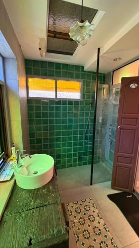 a green tiled bathroom with a sink and a shower at Cozy two-storey home in Ban Lam Praya Phai Rua