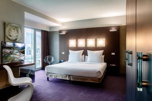 a hotel room with a bed and a television at Le Rex Hôtel in Tarbes