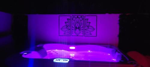 a purple room with a tub with a clock on it at Le Chalet romantique avec jacuzzi privatif in Lirac
