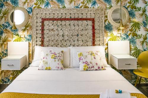 a bedroom with a white bed with floral wallpaper at Hotiday Ferrara Centro in Ferrara