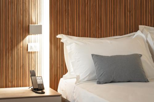 ein Bett mit Kissen und ein Telefon auf einem Tisch in der Unterkunft Hotel F52 in Parma