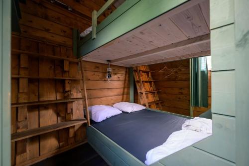 a bed in a wooden room with two pillows at Kampeerhut met gedeeld sanitair in Wintelre