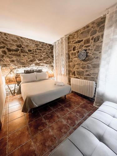 a bedroom with a bed and a stone wall at Casa As Fontes in Porqueirós