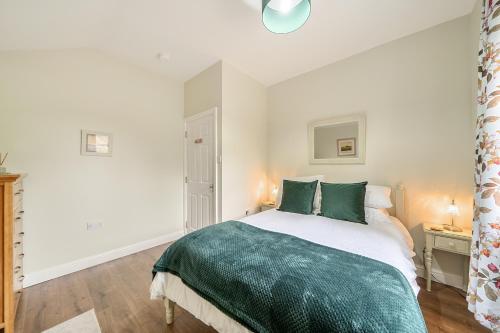 a white bedroom with a bed with green pillows at Central Ripon - Sleeps 3 - Garden - Pet Friendly in Ripon