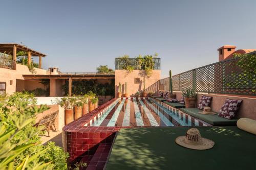 a swimming pool with green cushions next to a building at The Mellah Hotel in Marrakesh