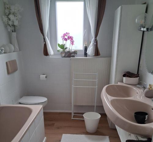 a bathroom with two sinks and a toilet and a window at Ferienhaus Spengler in Beuren