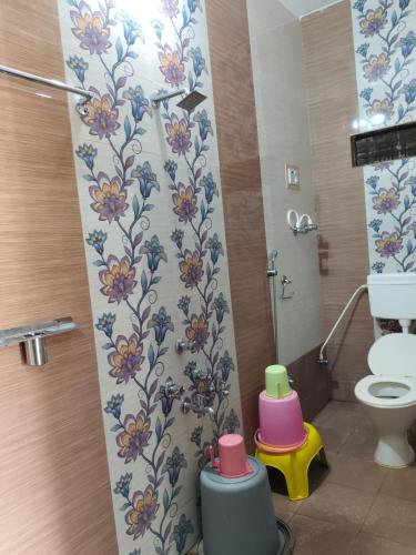 a bathroom with a toilet and a shower with flowers on the wall at Vinayaka Homestay Hampi in Hampi