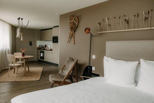 a hotel room with a bed and a dining room at OVERLOOK Lodge by CERVO Zermatt in Zermatt