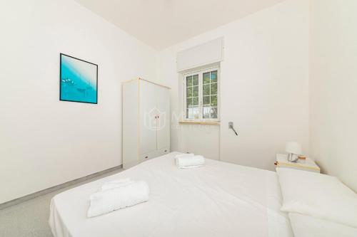 a white bedroom with a white bed and a window at Villa Cesare in Torre Specchia Ruggeri