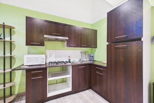 a kitchen with wooden cabinets and a microwave at Le Cocoon Fuchsia in Romilly-sur-Seine