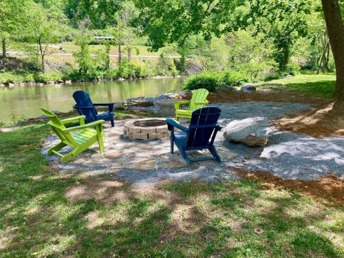 three chairs sitting around a fire pit next to a river at Full Stream Ahead in Whittier