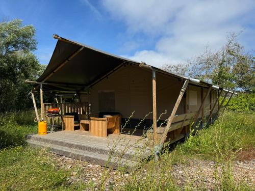 a black tent with a table and chairs in a field at Løkken Klit GLAMPING in Løkken