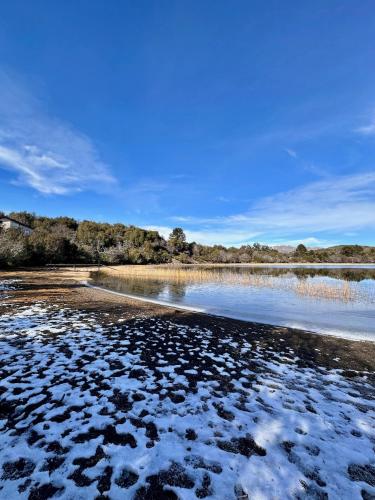 a beach with snow on the shore of a body of water at Estrellas de la Laguna in Villa Pehuenia