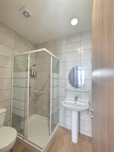 a bathroom with a shower and a sink and a toilet at Harrys Inn Guesthouse in Larnaca