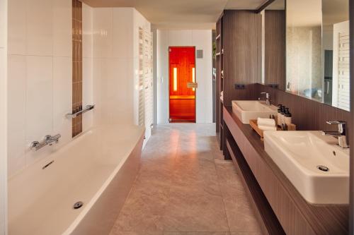 a bathroom with a tub and two sinks and a red door at Van der Valk Hotel Amersfoort-A1 in Amersfoort