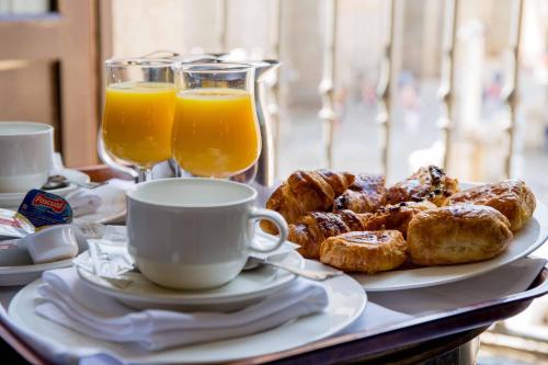 a table with a plate of pastries and glasses of orange juice at Palacio de los Velada in Avila