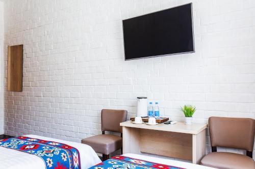 a room with two beds and a tv on a wall at Solief Hotel in Tashkent