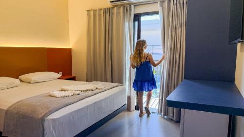 a woman looking out the window of a hotel room at Blie Hotéis - Inauguração in Bonito