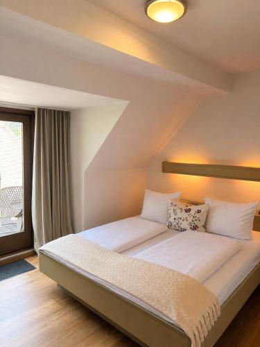 a bedroom with a large bed with white sheets at Galerie Riesling in Trittenheim