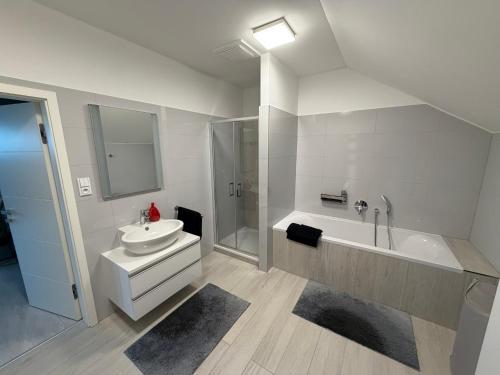 a white bathroom with a sink and a bath tub at La Brloh Pardubice in Pardubice