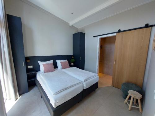 a bedroom with a bed with white sheets and pink pillows at Comfort bungalow 02 met jacuzzi in Putten