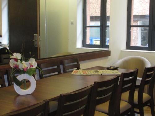 a dining room table with a vase of flowers on it at Hôtel le Pastel in Toulouse